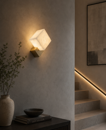 Petra geometric wall sconce in natural alabaster with brushed brass base, warm ambient lighting for modern interior