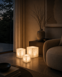 Petra Ground alabaster table lamp cluster with organic veining and warm ambient glow beside beige armchair
